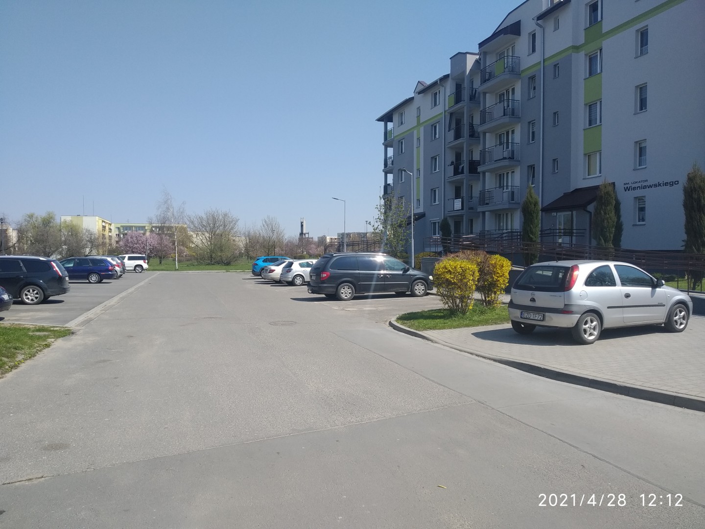 Na zdjęciu widać uliczkę między blokami i parkujące samochody
